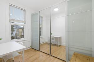 ein weißes Zimmer mit einem Tisch und einer Glaswand in der Unterkunft 1-Bed Flat, home office and garden in Croydon + 6 Fotos
