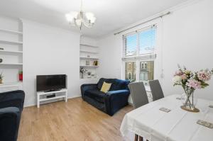 ein Wohnzimmer mit einem Tisch, einem Sofa und einem TV in der Unterkunft 1-Bed Flat, home office and garden in Croydon