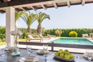 a table with a plate of fruit on it next to a swimming pool at Los Olivos - Casa rural en exclusiva finca privada in Sant Lluis +27 photos
