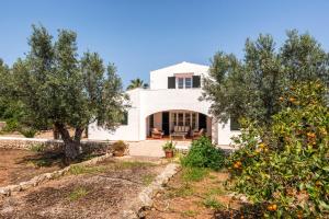 a white house with trees in front of it at Los Olivos - Casa rural en exclusiva finca privada in Sant Lluis