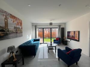 a living room with two blue chairs and a couch at New Build-Free Parking-EV charging-3 Bedrooms-3 showers in Cheshunt