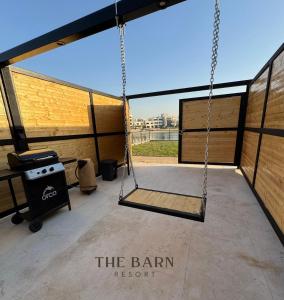 eine Schaukel auf einer Terrasse mit Grill in der Unterkunft The Barn Resort Sea View منتجع ذا بارن in An Nāmī