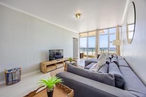 a living room with a large couch and a television at Atlantic Haven in Bloubergstrand