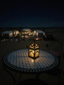 a lantern sitting on a table on the beach at night at Treasure Desert Camp in Merzouga