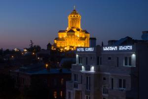 un bâtiment avec une tour éclairée la nuit dans l'établissement Hotel Gureli, à Tbilissi