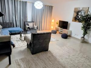a living room with a couch and chairs and a tv at 3 bedrooms apartment in Al Rehab city in New cairo