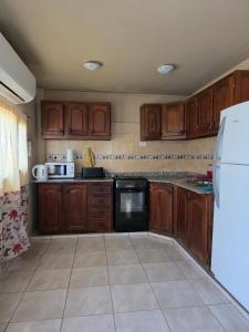 Una cocina con gabinetes de madera y un refrigerador blanco. en Timotea, en Perito Moreno