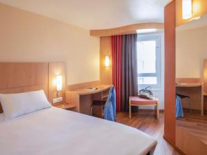 a hotel room with a bed and a desk and a window at ibis Tours Centre Gare in Tours