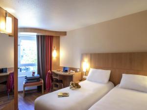 a hotel room with two beds and a desk at ibis Tours Centre Gare in Tours