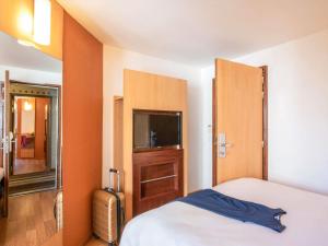 a bedroom with a bed and a tv and a mirror at ibis Tours Centre Gare in Tours +107 photos
