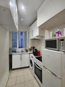 eine weiße Küche mit Mikrowelle und Geschirrspüler in der Unterkunft Évasion Parisienne exelmans et Tour Eiffel in Paris + 31 Fotos