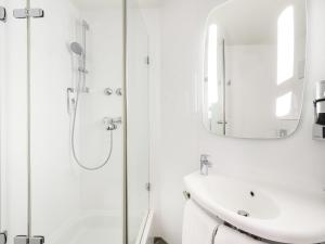 Un baño blanco con lavabo y espejo. en ibis Frankfurt Centrum, en Frankfurt 130 fotos más