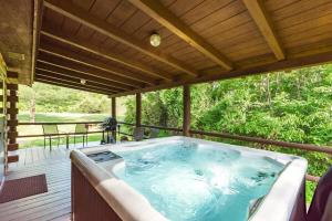 ein Whirlpool auf einer überdachten Terrasse in der Unterkunft Secluded Log Cabin with a Hot Tub near Bridle Trails in Logan, Ohio in Cedar Grove