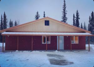 una casa rossa con neve per terra di Northern Lights Getaway! a North Pole