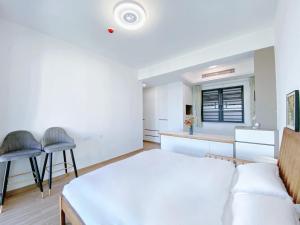 a bedroom with a bed and two chairs and a kitchen at Nearby Time in Beihai