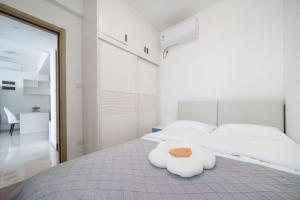 a white bed with a towel animal on it at Nearby Time in Beihai