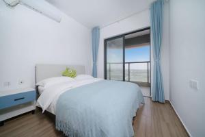 a white bedroom with a bed and a large window at Nearby Time in Beihai