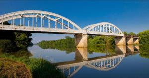 Chambre d'hôtes Chez Papi,meublé tourisme 3 étoiles في Josse: جسر فوق نهر وانعكاسه في الماء +3 صور