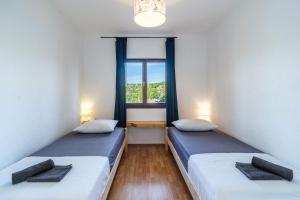 twee bedden in een kamer met een raam bij Villa Tudor Mit Atemberaubender Aussicht in Bobovišća