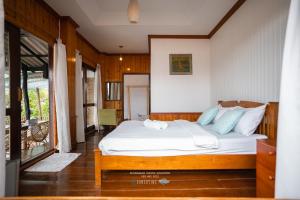 a bedroom with a bed with white sheets and blue pillows at คลองมาดโฮสเทลเกาะกูด Klongmad Hostel Kohkood  +5 photos