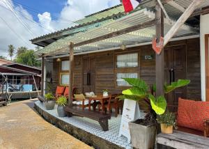a wooden house with a wooden table and chairs at คลองมาดโฮสเทลเกาะกูด Klongmad Hostel Kohkood  +14 photos