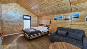 a bed and a couch in a room with wooden walls at Aiwa Eco Hotel in Karakol