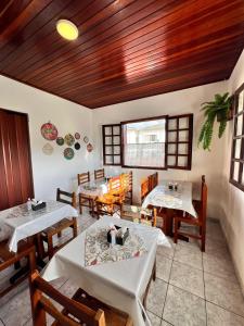 un restaurant avec des tables blanches et des plafonds en bois dans l'établissement POUSADA GIRASSOL, à Santo Antônio do Pinhal