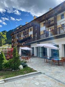 Un hotel con mesas y sombrillas en un patio. en Maison Poluc - Cadeau des Alpes, en Champoluc