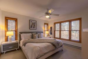 een slaapkamer met een bed, een plafondventilator en ramen bij The Raven in Beech Mountain