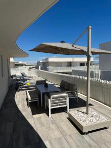 a patio with a table and an umbrella on a roof at Exceptionnel appartement avec vue mer in Vendres-Plage