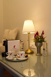 a table with a lamp and two cups and a laptop at Vila Băncii 1888 by SunGarden in Băile Herculane