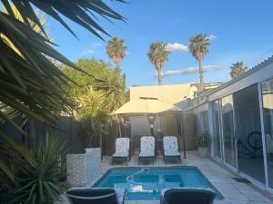 a house with a swimming pool and palm trees at Home Away From Home 6 minutes away from beach in Cape Town