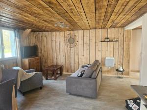a living room with a couch and a wooden ceiling at Le ptit clos in Les Combes