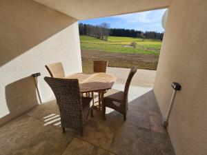 a table and chairs on a balcony with a view of a field at Le ptit clos in Les Combes