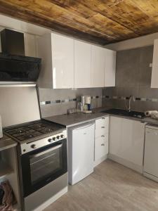 eine Küche mit weißen Schränken und einem Herd mit Backofen in der Unterkunft Le ptit clos in Les Combes