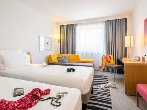 une chambre d'hôtel avec deux lits et un bureau dans l'établissement Novotel Marne-la-Vallée Noisy-le-Grand, à Noisy-le-Grand