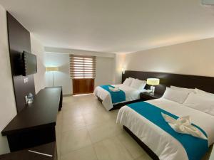 ein Hotelzimmer mit zwei Betten und einem Fernseher in der Unterkunft Hotel María del Carmen in Jalpan de Serra + 14 Fotos