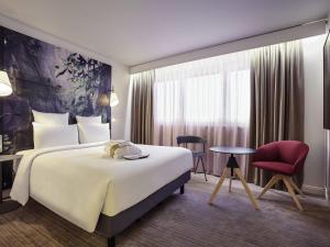 a hotel room with a large bed and a chair at Mercure Paris La Défense in Courbevoie +113 photos