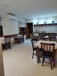 Un comedor con mesas y sillas y una cocina. en Hotel Pousada Garoupas, en São Sebastião