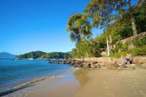 una playa con un grupo de personas sentadas en la orilla en CASA DA ILHA INN and SPA Anexo2, en Angra dos Reis
