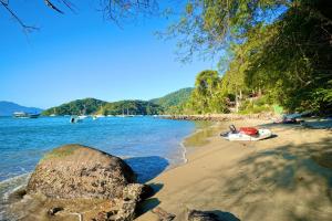una playa con una roca y un barco en la orilla en CASA DA ILHA INN and SPA Anexo2, en Angra dos Reis