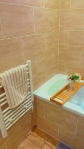 a bathroom with a tub with a towel and a plant at Maxismile Haven in Southend-on-Sea