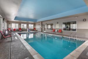 una piscina en un hotel con sillas y mesas rojas en Best Western Plus Tech Medical Center Inn, en Lubbock