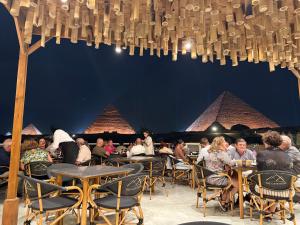 a group of people sitting at tables in front of pyramids at The Gate Hotel Front Pyramids & Sphinx View in Cairo