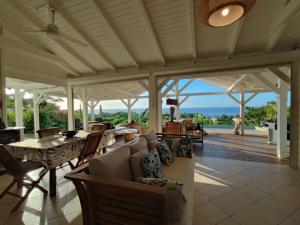 an outdoor patio with tables and chairs and a view of the ocean at Villa Franco - Plage de Leroux à 600m - Vue mer exceptionnelle in Deshaies