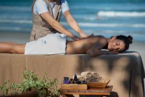 a woman getting a massage at the beach at Hotel Spa Nau Royal in Camburi