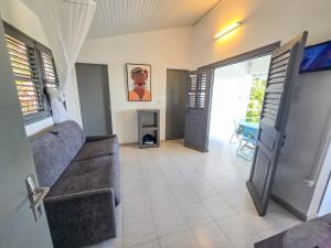 a living room with a couch and an open door at Lauramar Avocado - Vue Mer et Montagne in Le Morne aux Bœufs