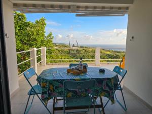 a table on a balcony with a view of the ocean at Lauramar Avocado - Vue Mer et Montagne in Le Morne aux Bœufs