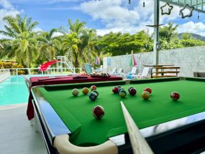 a pool table with balls on it next to a swimming pool at Avare House Krabi in Ao Nam Mao