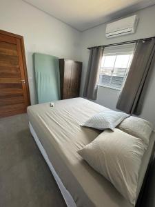 ein Schlafzimmer mit einem großen weißen Bett mit einem Fenster in der Unterkunft Casa garagem camionete, 2 quartos, espaço para 6 pessoas, casa completa, 5min Centro - Casa 5 in Sinop